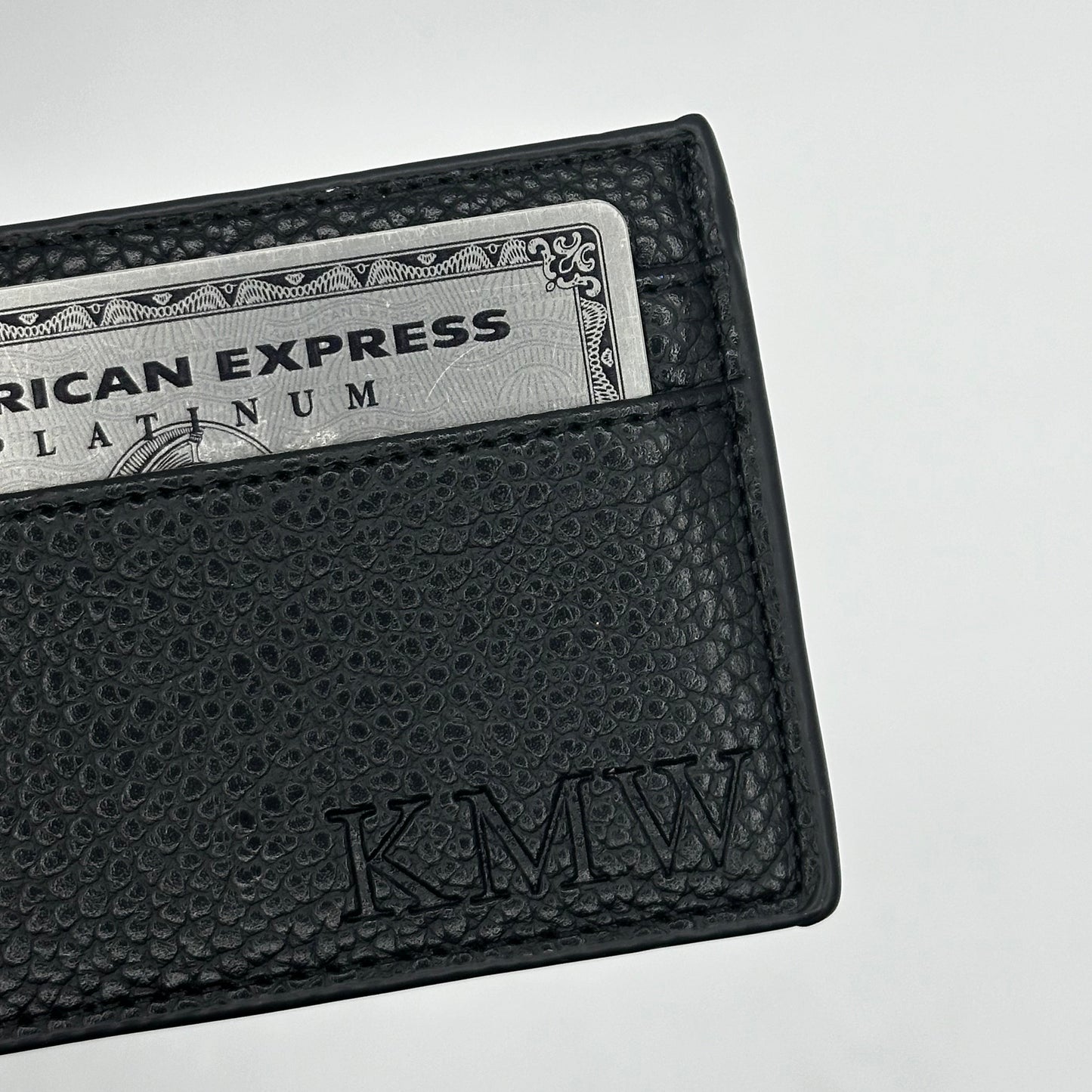 Black leather wallet with American Express card on a light gray background