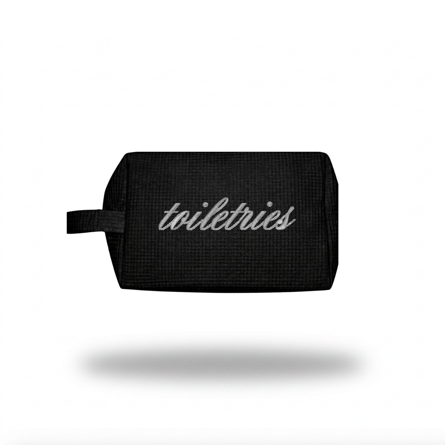 A black textured toiletry bag with a small carrying loop and the word 'toiletries' printed in white script on the front, shown against a plain white background with a soft drop shadow.