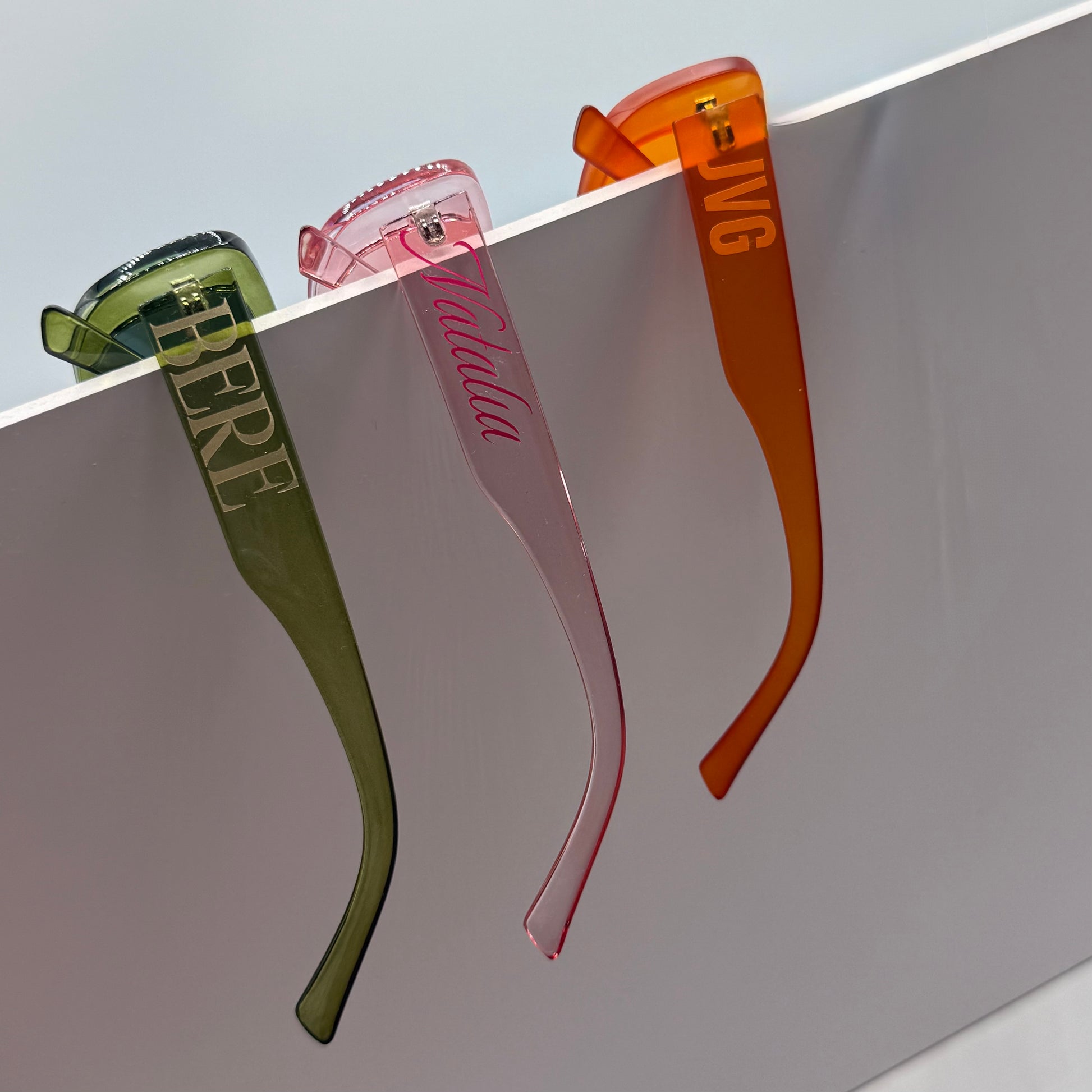Four hair straighteners in green, pink, and orange on a light gray background