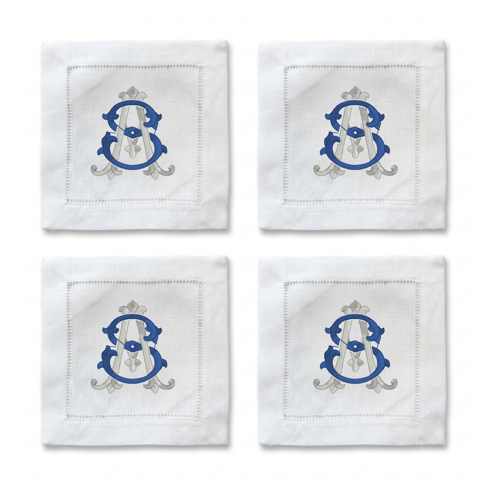 Four white embroidered cocktail napkins arranged in a 2x2 grid, each featuring a blue and silver monogram crest with a white veil motif.