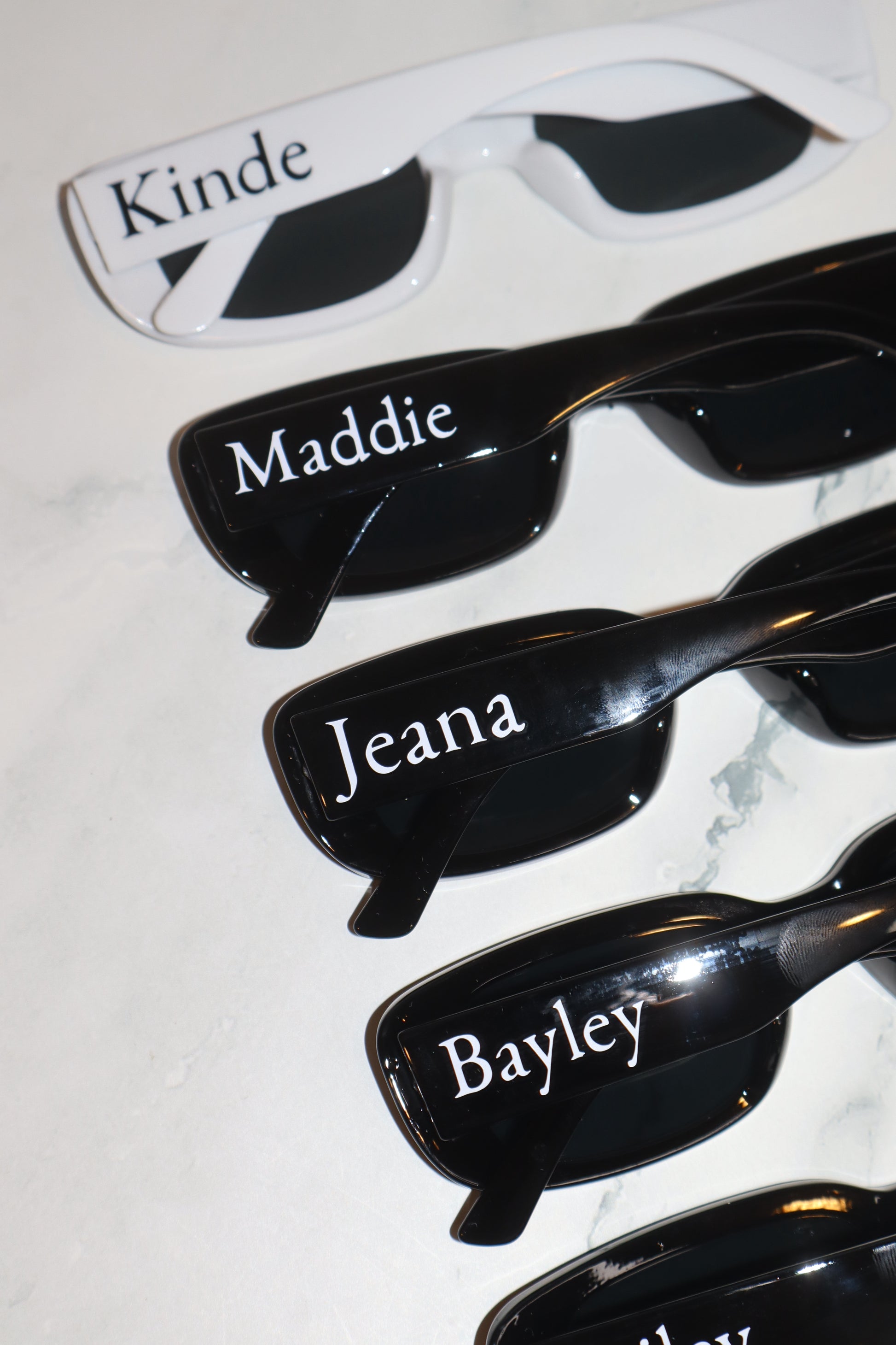 Black sunglasses with names engraved on a light gray background