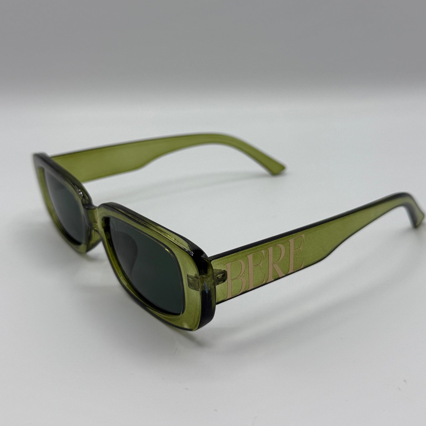 Green sunglasses with dark lenses on a white background
