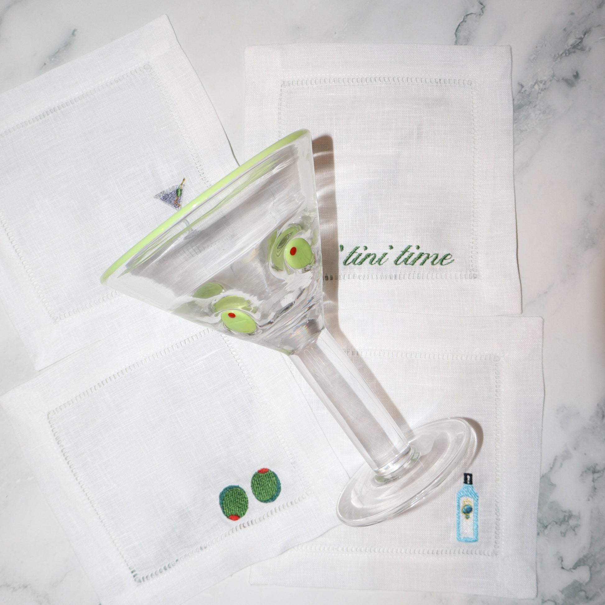 Glass with green olives on a marble surface