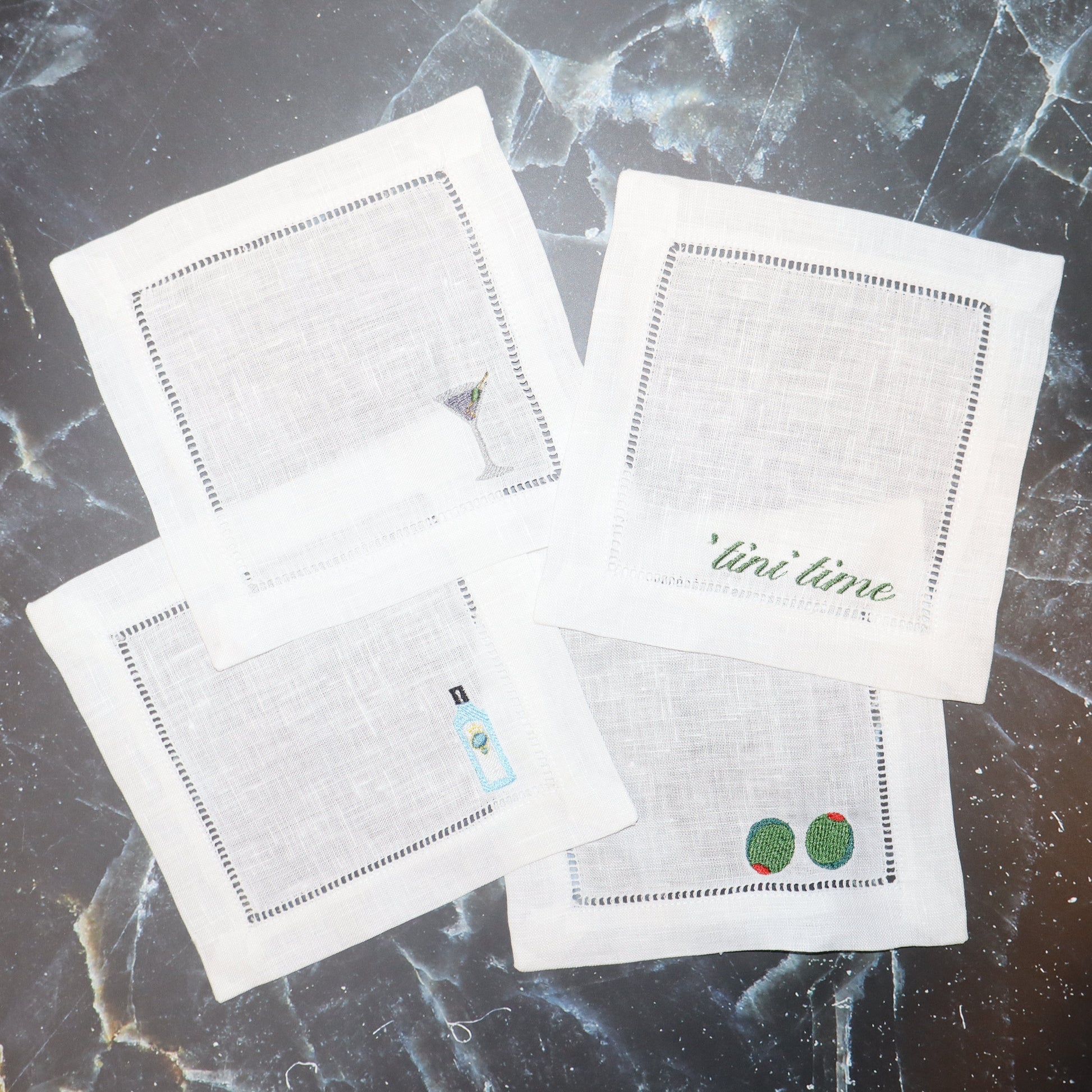 Four white cards with printed designs on a marble surface