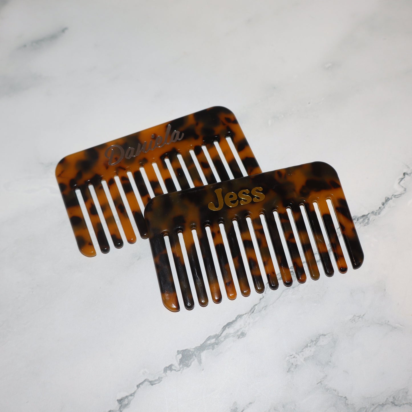 Two tortoiseshell combs on a marble surface