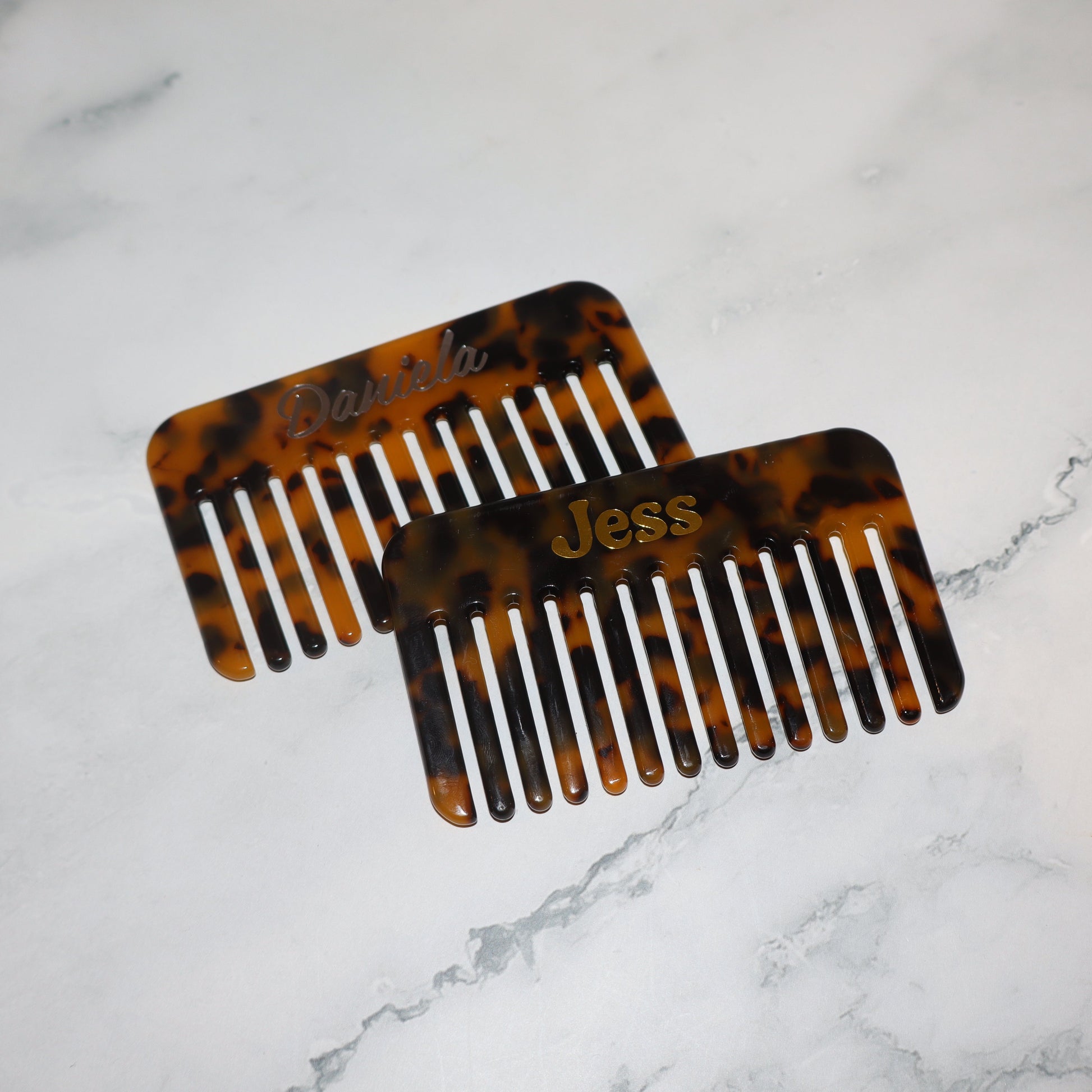 Two tortoiseshell combs on a marble surface