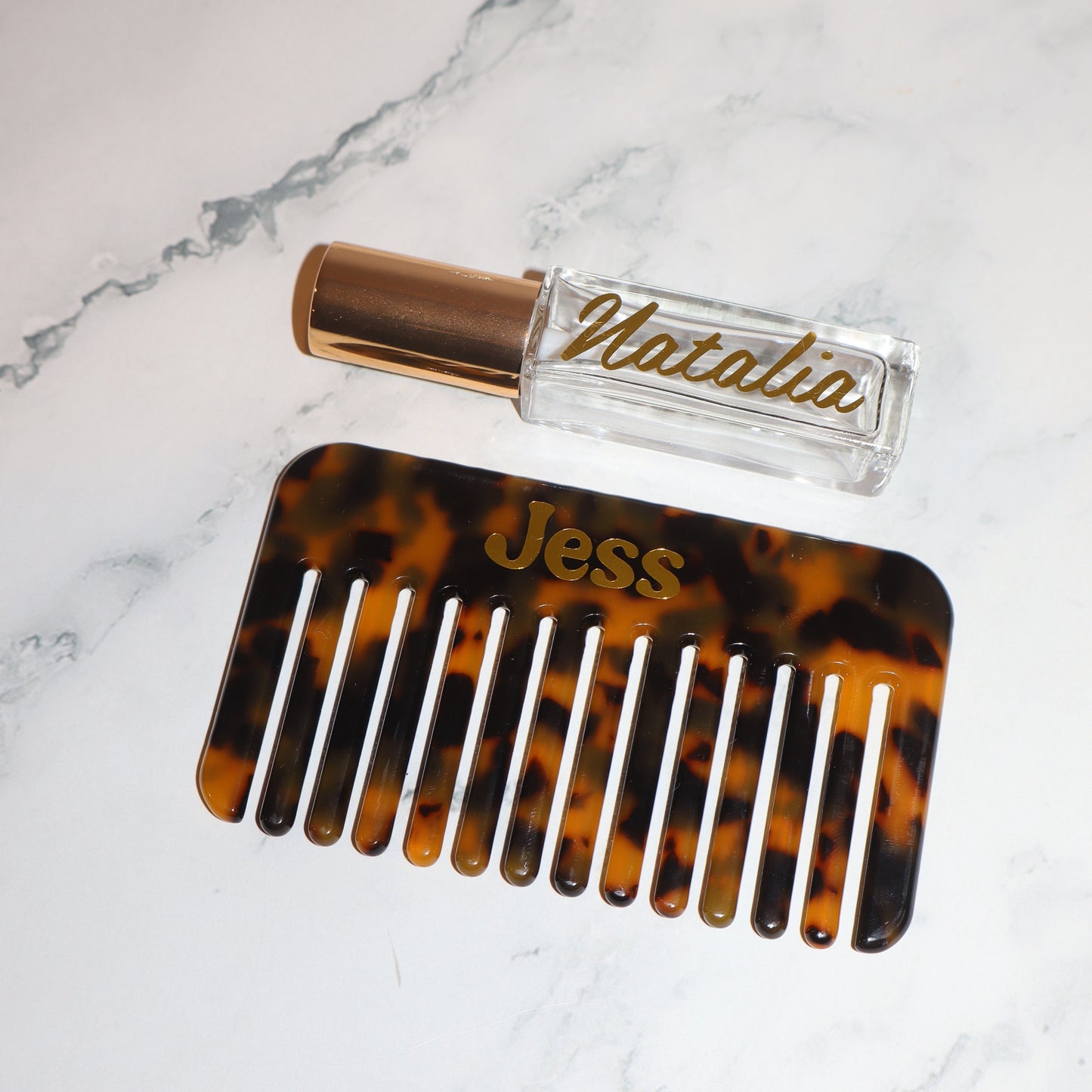 Tortoiseshell comb and small bottle labeled 'Natalia' on a marble surface