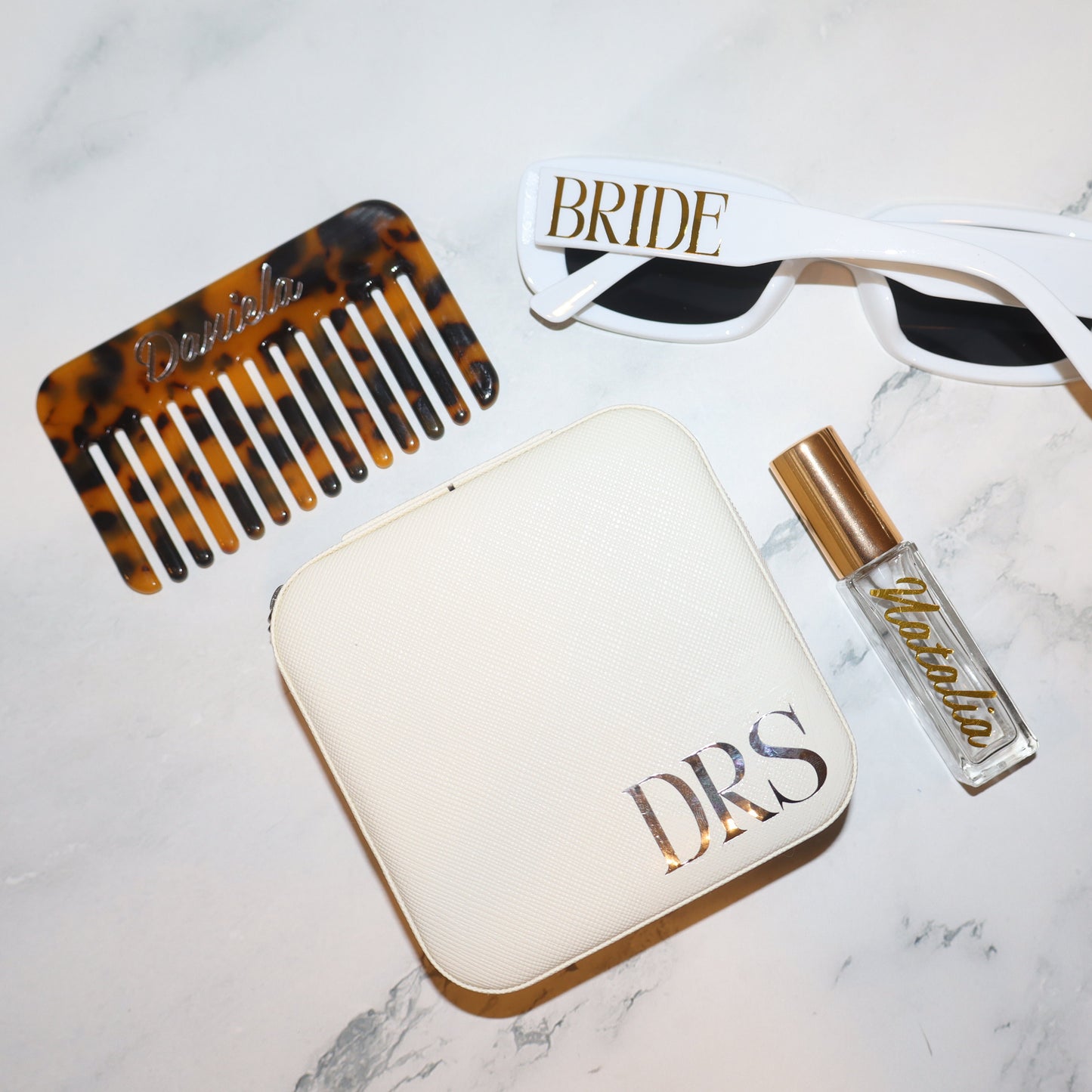 Comb, sunglasses, pouch, and perfume bottle on a marble surface