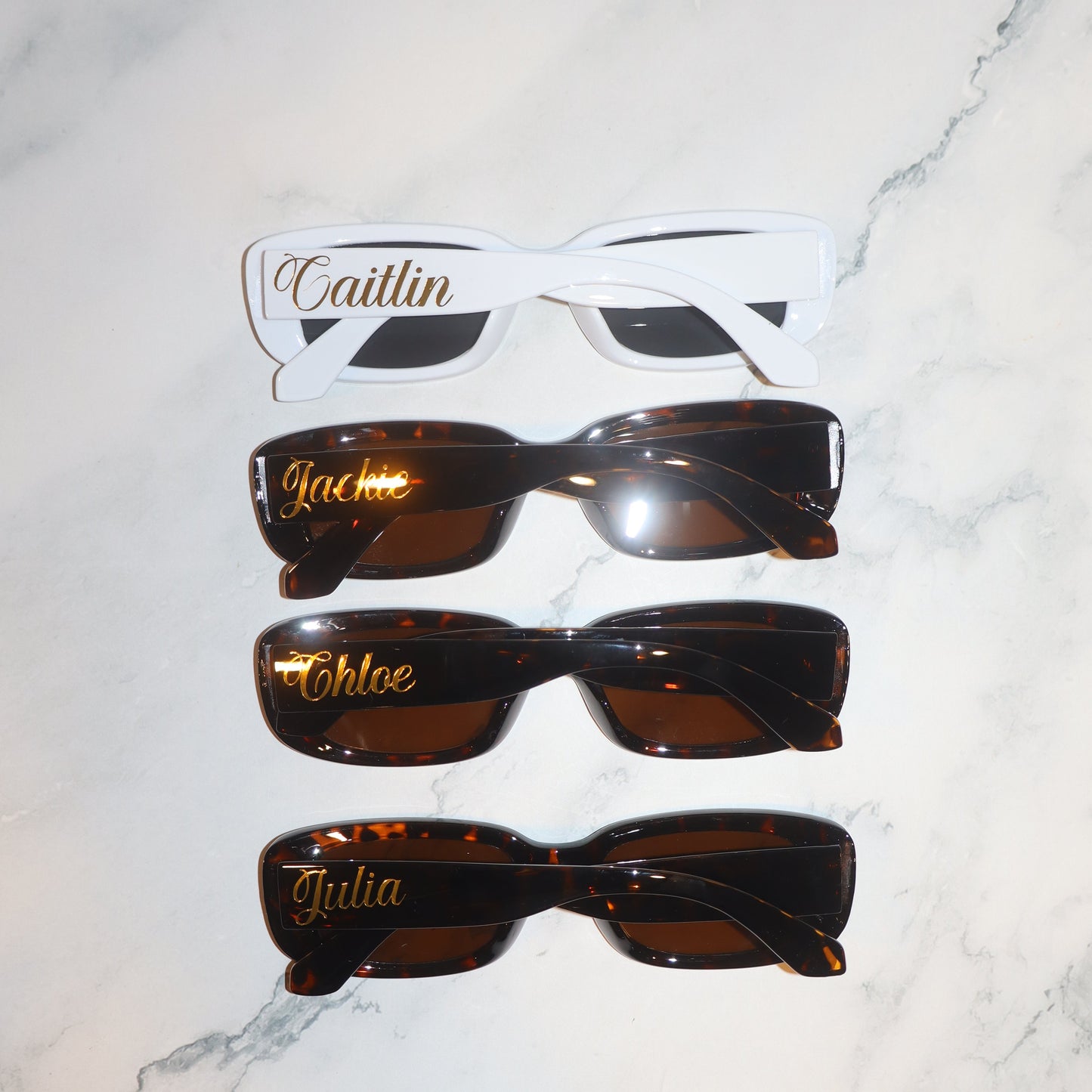 Set of sunglasses with personalized names on a marble surface