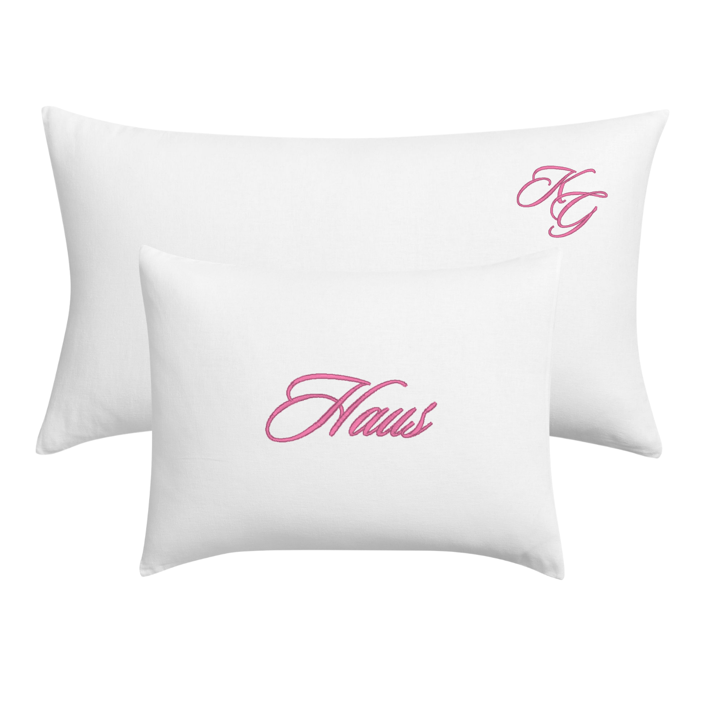Two white rectangular pillows, one larger and one smaller, both featuring pink cursive script embroidery on the front. The larger pillow displays 'HG' and the smaller pillow displays 'Haus'.